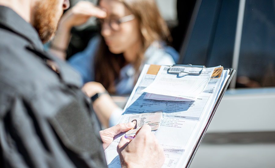 A policeman is writing a ticket for no insurance to a woman